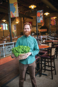 Nick Pagan '15, pictured in the Clark cafeteria, holds a basket of lettuce he harvested from the university's Freight Farm.