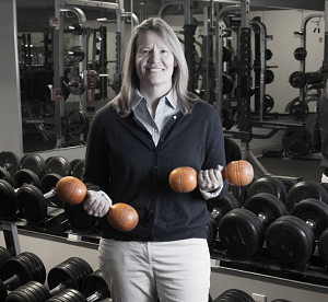 Athletic Director Trish Cronin tries out some wooden dumbbells.