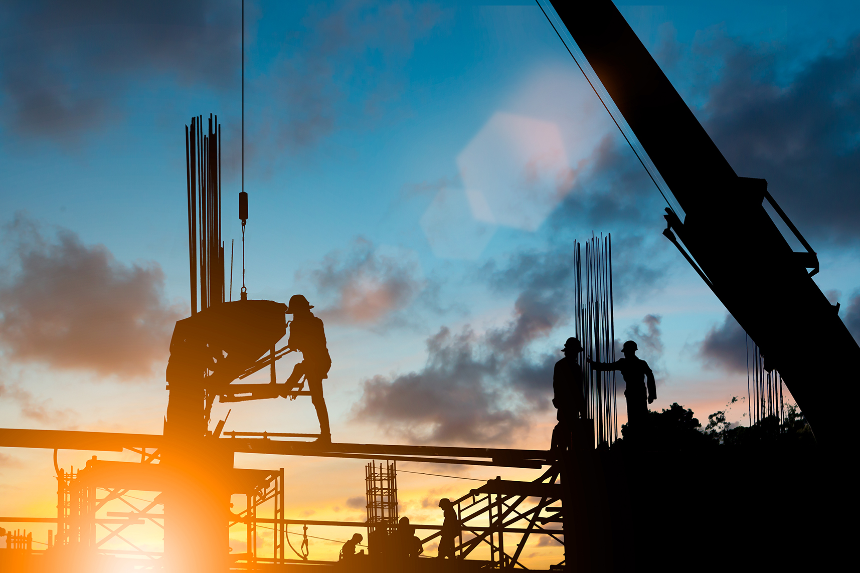 Silhouette of construction workers at site, with sun setting