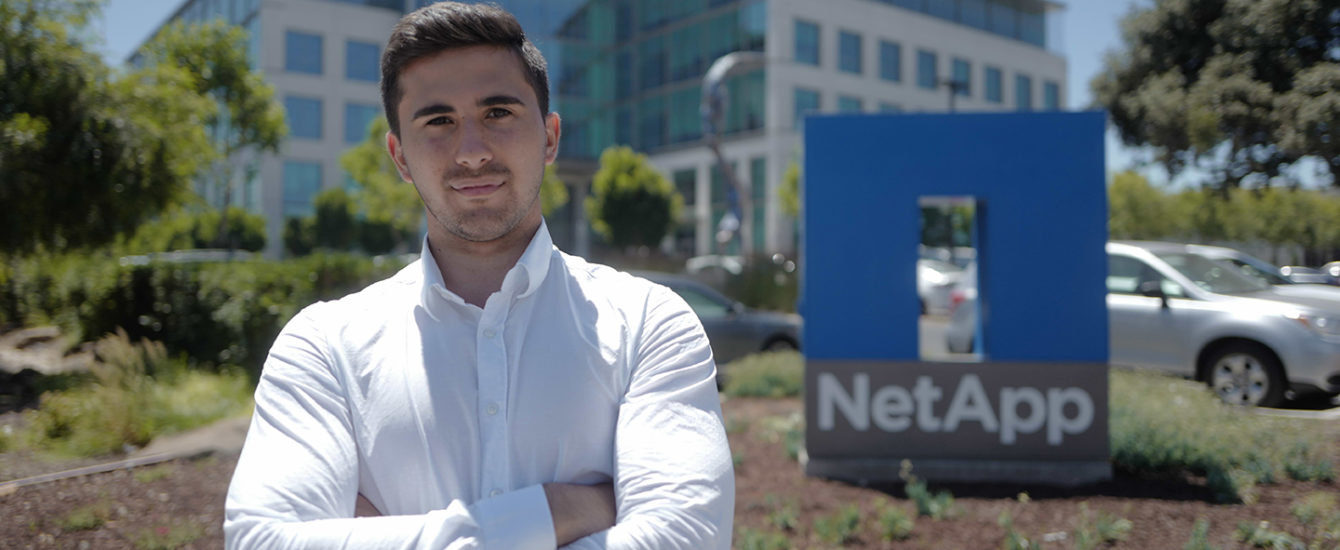 Teodor Nicola-Antoniu standing in front of NetApp sign outside building