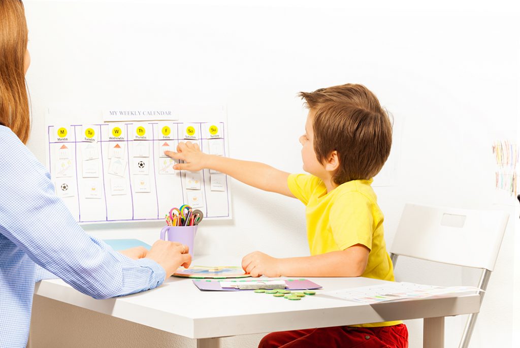 Boy pointing at schedule on a wall