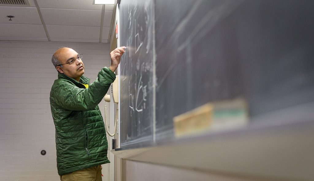 Physics professor Arshad Kudrolli working at a chalkboard 