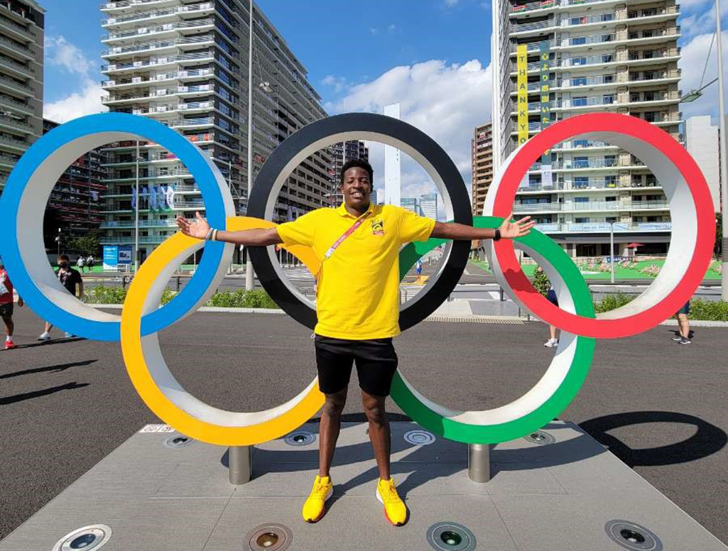 Atuhaire Ambala standing in front of Olympic rings in Tokyo