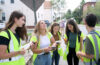 five students in green safety vests stand together while conducting research in a Worcester neighborho