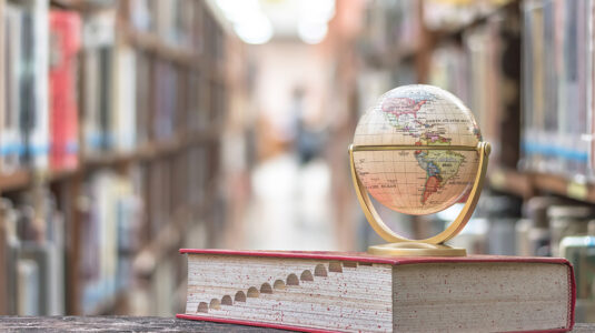 Globe sitting on top of book in academic library