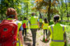 hero fellows wearing bright green vests walk through forest