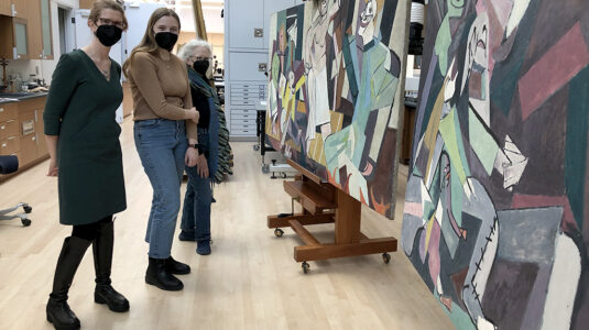 From left: Professor Kristina Wilson, Peyton Dauley ’24, and Erica Hirshler, senior curator of American paintings at the Museum of Fine Arts, look at Karl Knaths’ “Day of Atonement” in the museum’s conservation lab.