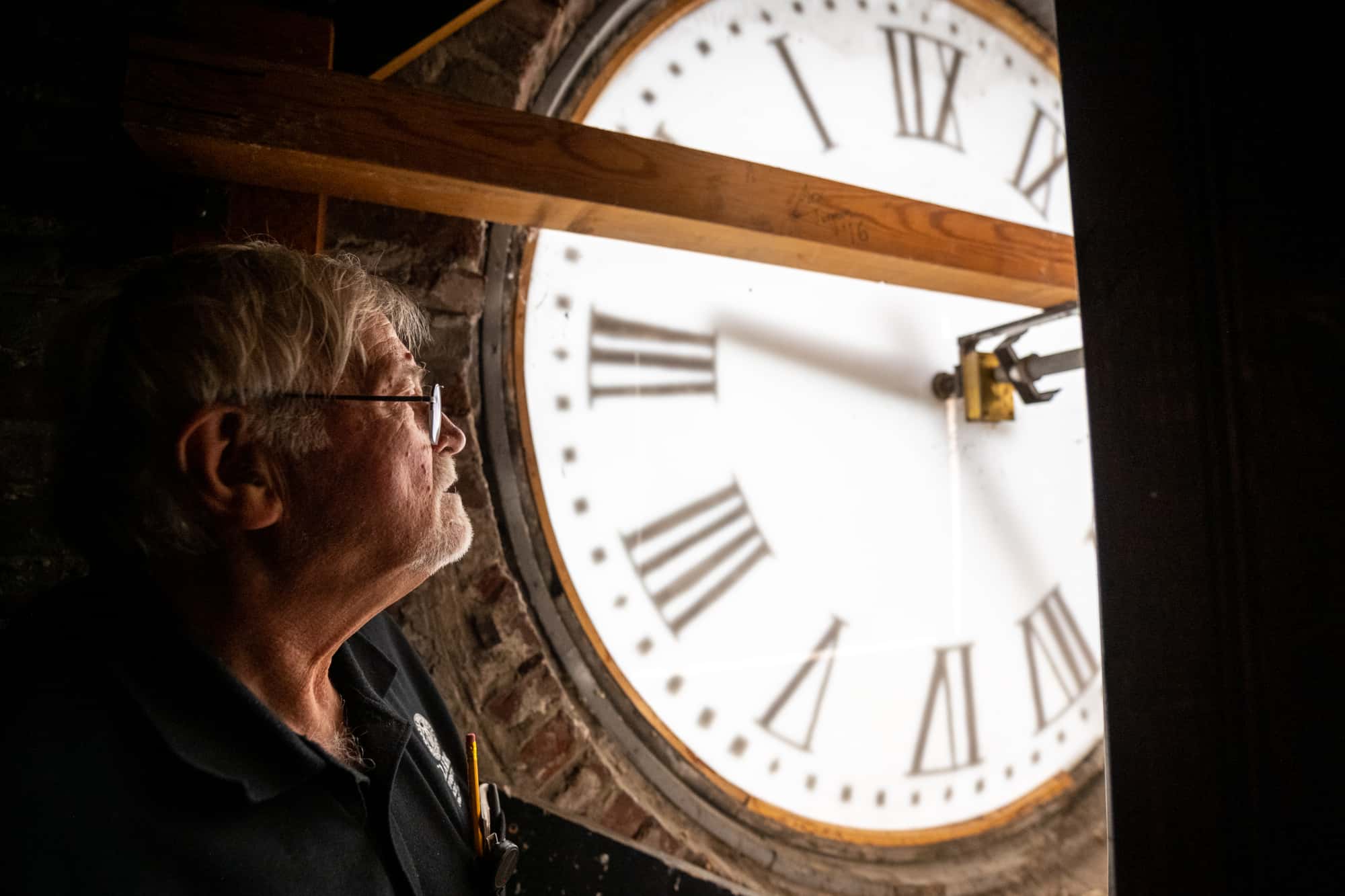 a man inspects the workings of a clock tower