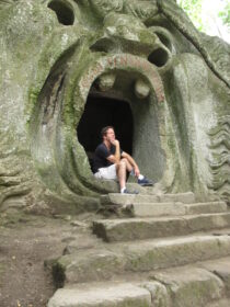 John Garton sits at "Hell Mouth" sculpture in Bomarzo, Italy