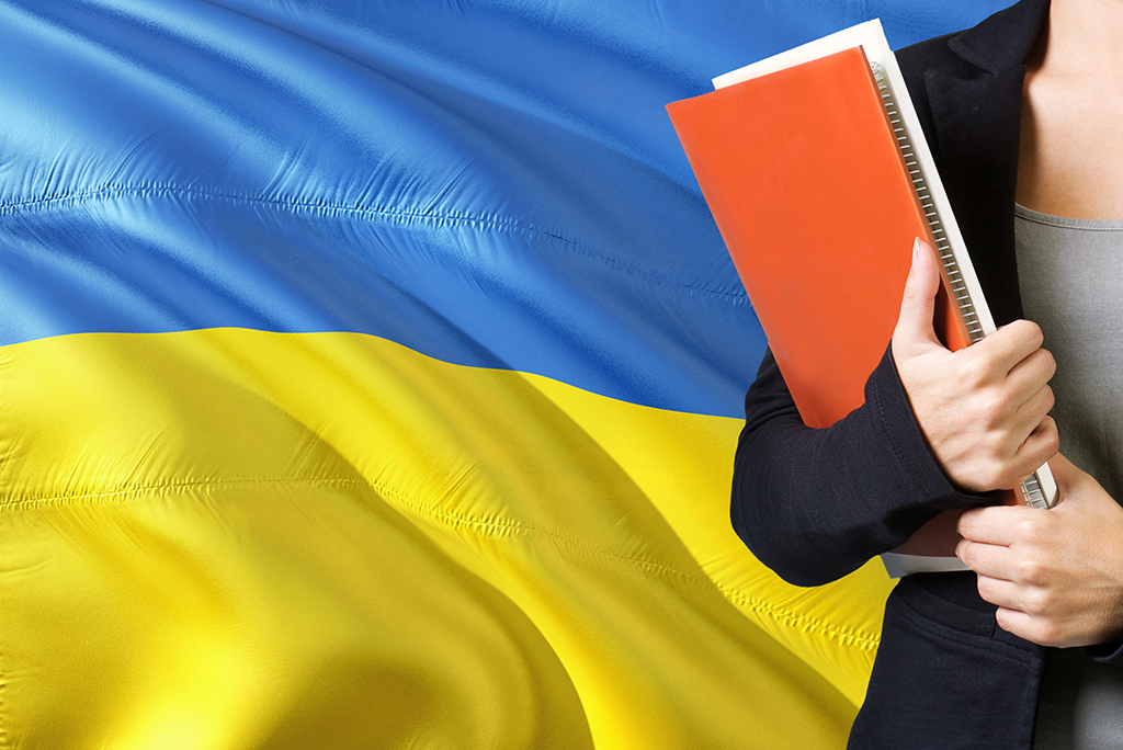 Student with books in front of Ukraine flag