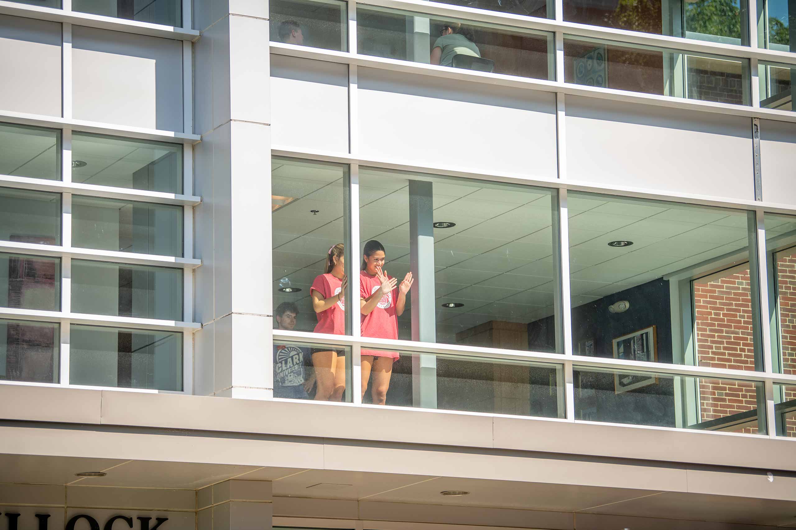 Students looking out towards campus from inside a glass walled building