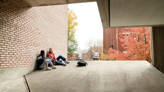Students sitting against brick wall