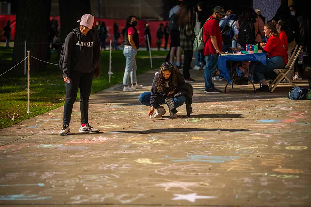 Students making chalk drawings on the sidewalk in Atwood Plaza, Clark University to celebrate #FreshCheckDay