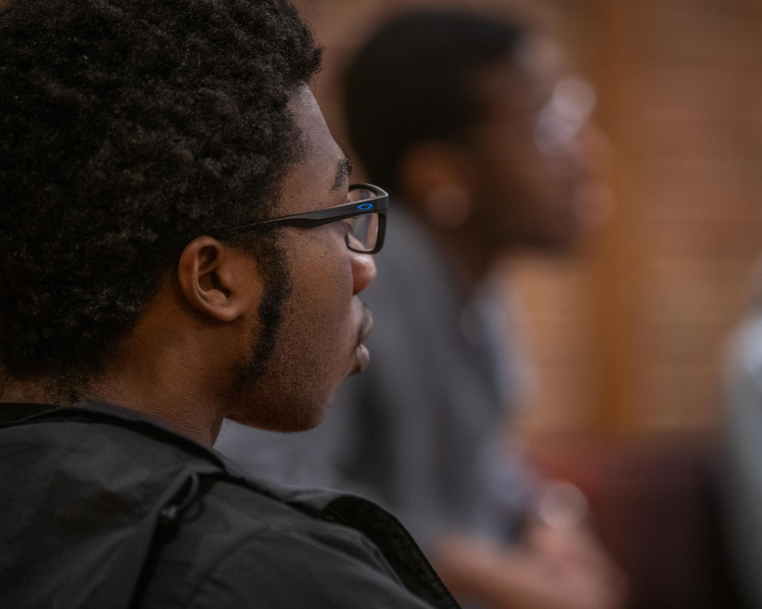 Profile portrait of a student listening to the conversation during a a gathering of the Men of Color Alliance at Clark University