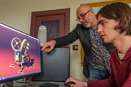 Professor Michael Swartz works on computer with a student