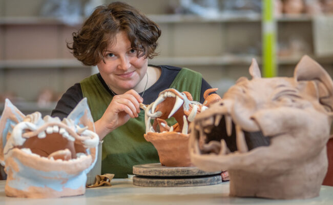 Brynn Kevin working on a clay dragon in an art studio