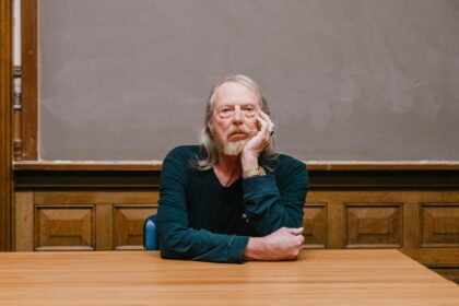 professor sitting at table with head in hand