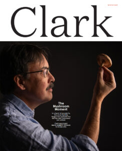 Cover of the winter 2024 edition of Clark Magazine, with the cover story entitled The Mushroom Moment showing Clark mycologist David Hibbett in profile holding up a mushroom.