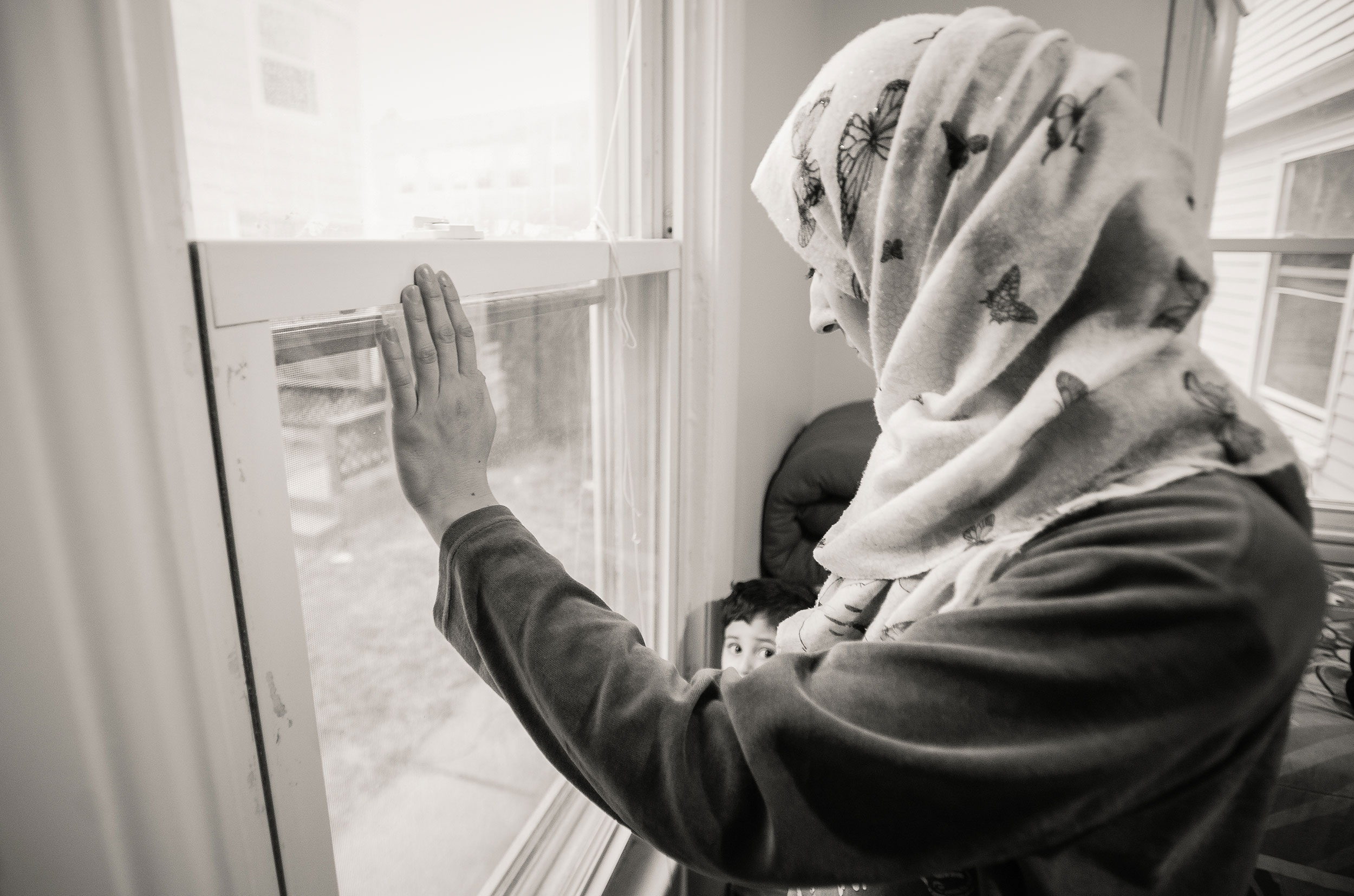 Refugee looking holding her child and looking out the window