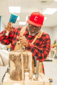 man uses tools to sculpt wood