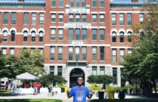 Student poses in front of brick building