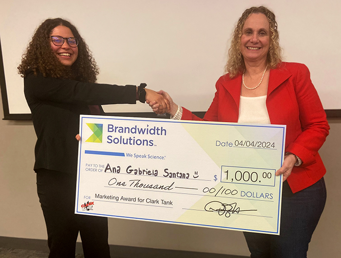 Ana Gabriela Santana ’26, winner of the marketing pitch competition, receives her check from Debra Harrsch ’80, president and CEO of Brandwith Solutions.