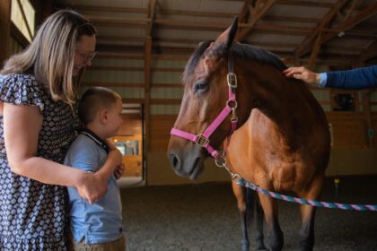 mom and boy look at horse